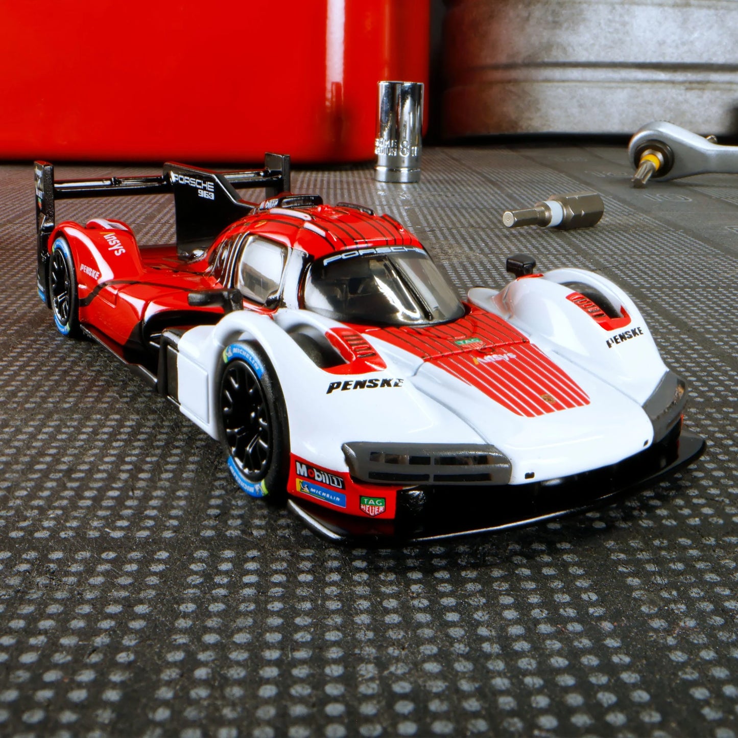 Hot Wheels Elite 64 Porsche 963 in Penske Team livery, featuring red, white, and black racing colors, detailed aero bodywork, and Real Riders wheels.