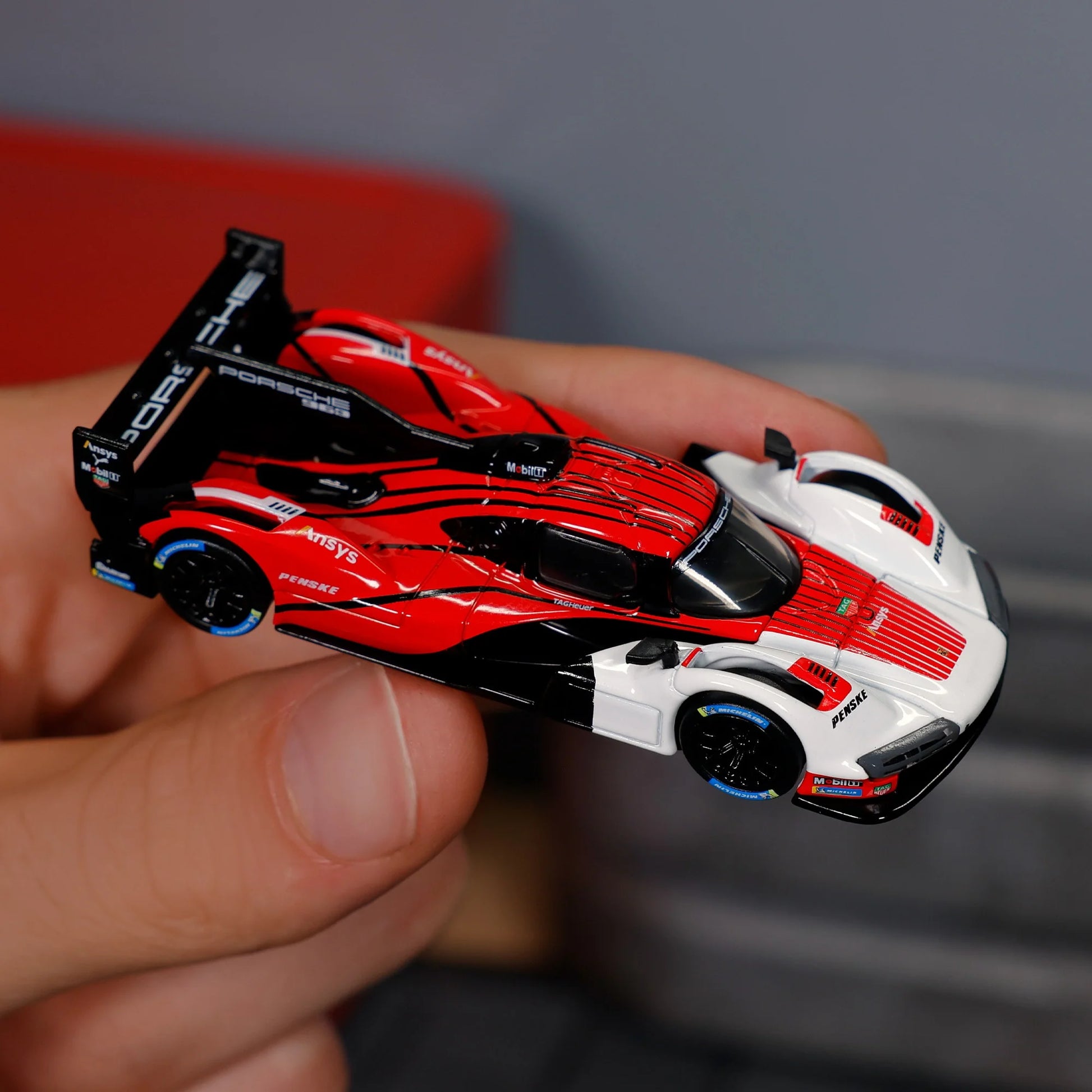 Hot Wheels Elite 64 Porsche 963 in Penske Team livery, featuring red, white, and black racing colors, detailed aero bodywork, and Real Riders wheels.