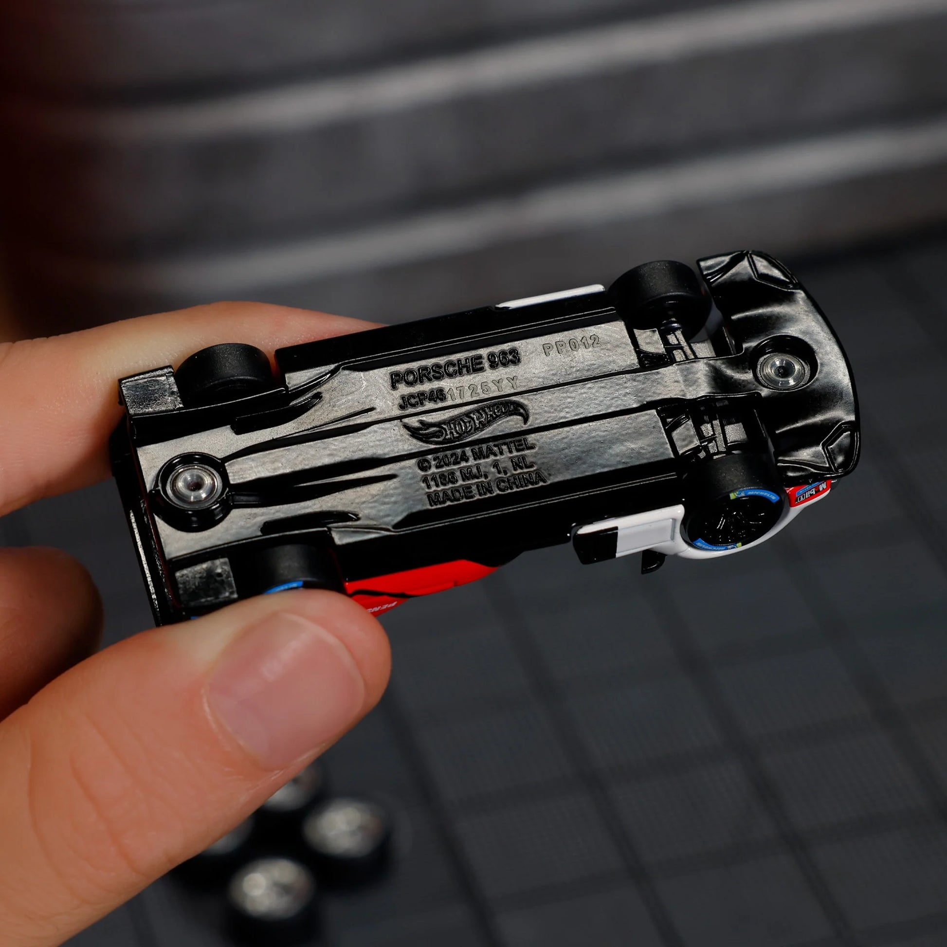 Hot Wheels Elite 64 Porsche 963 in Penske Team livery, featuring red, white, and black racing colors, detailed aero bodywork, and Real Riders wheels.