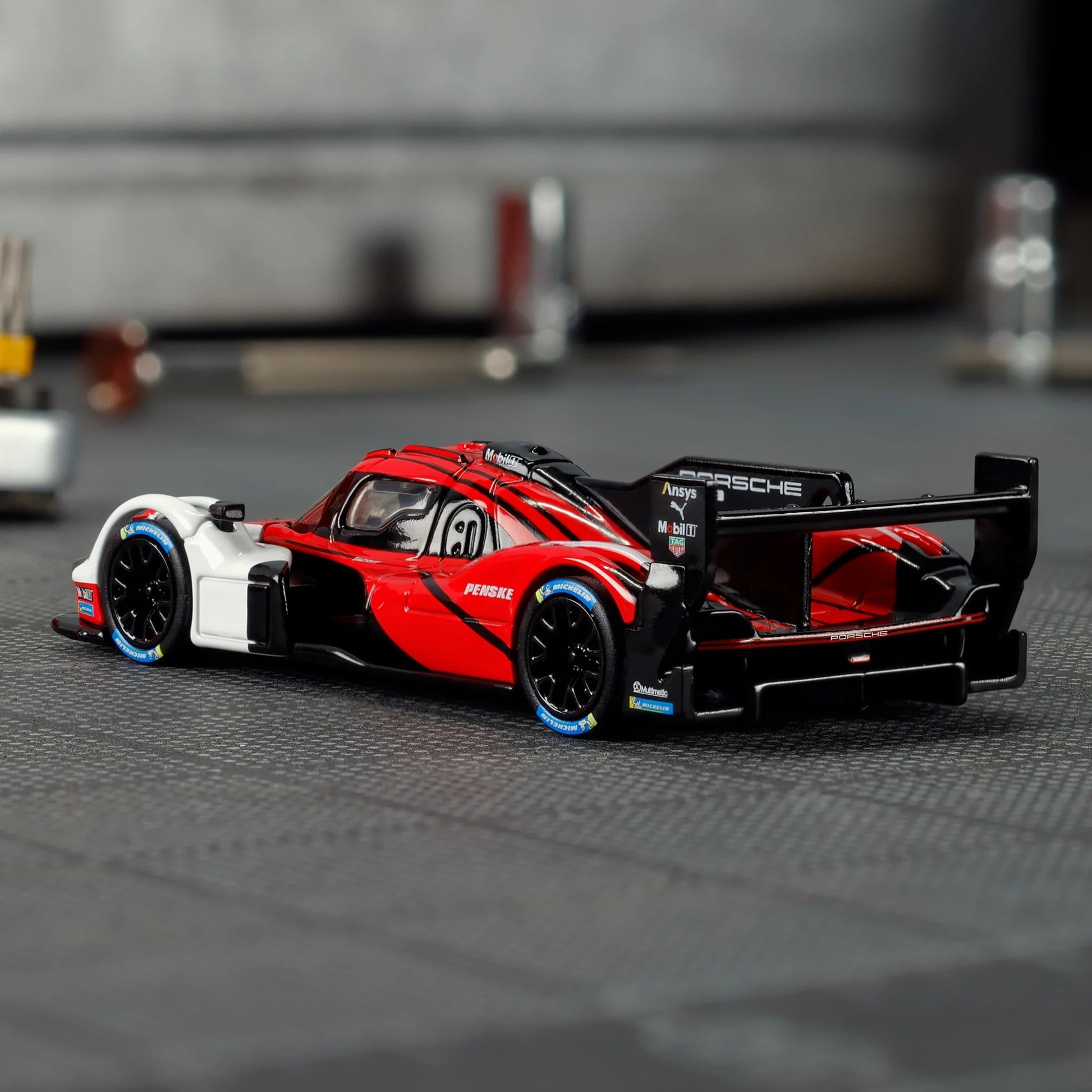 Hot Wheels Elite 64 Porsche 963 in Penske Team livery, featuring red, white, and black racing colors, detailed aero bodywork, and Real Riders wheels.