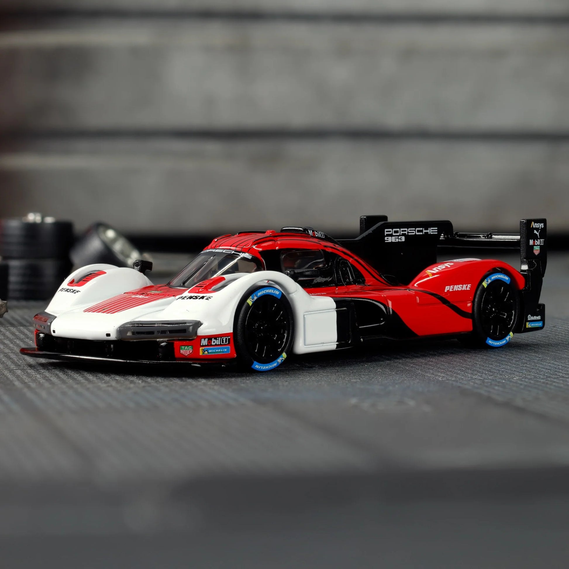 Hot Wheels Elite 64 Porsche 963 in Penske Team livery, featuring red, white, and black racing colors, detailed aero bodywork, and Real Riders wheels.