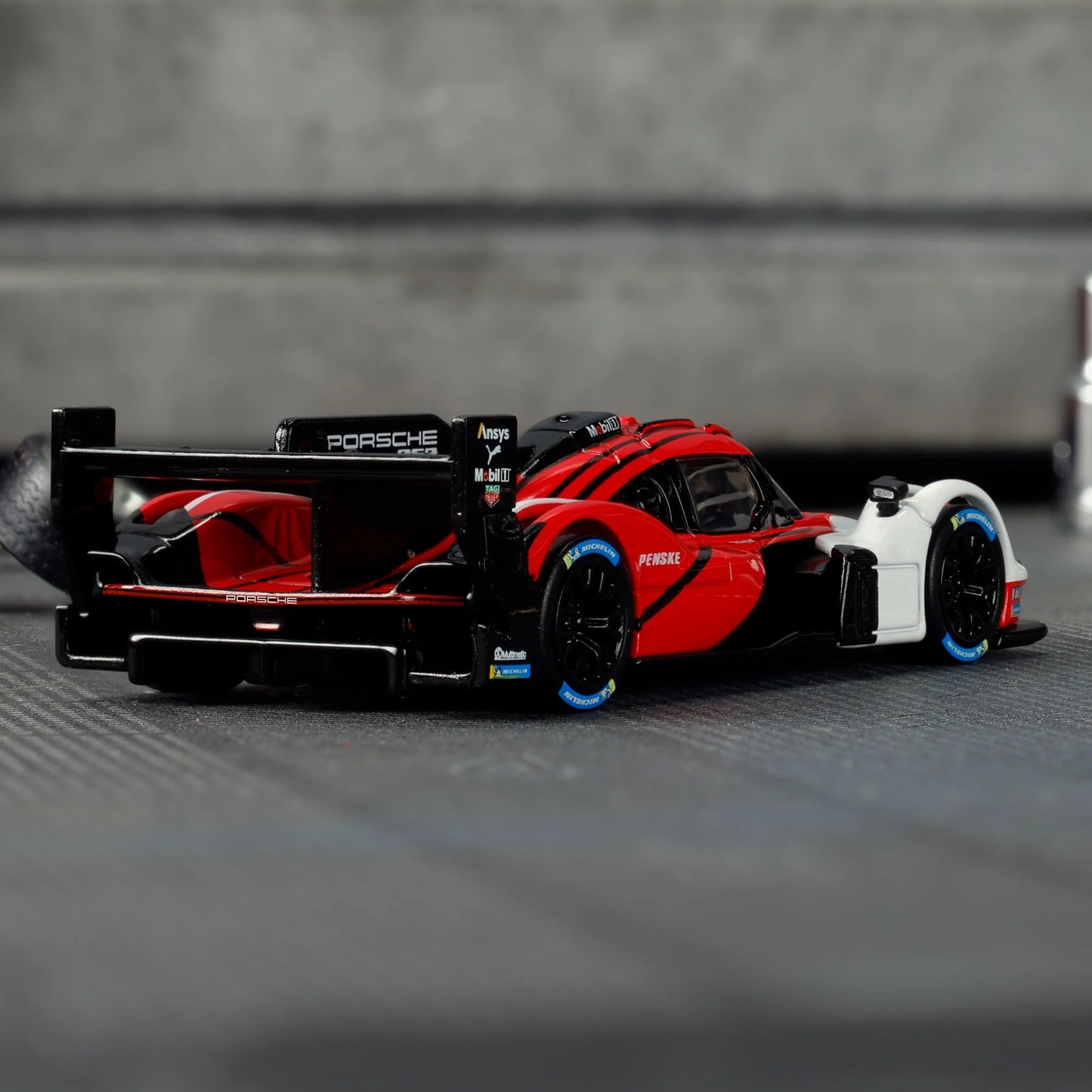 Hot Wheels Elite 64 Porsche 963 in Penske Team livery, featuring red, white, and black racing colors, detailed aero bodywork, and Real Riders wheels.