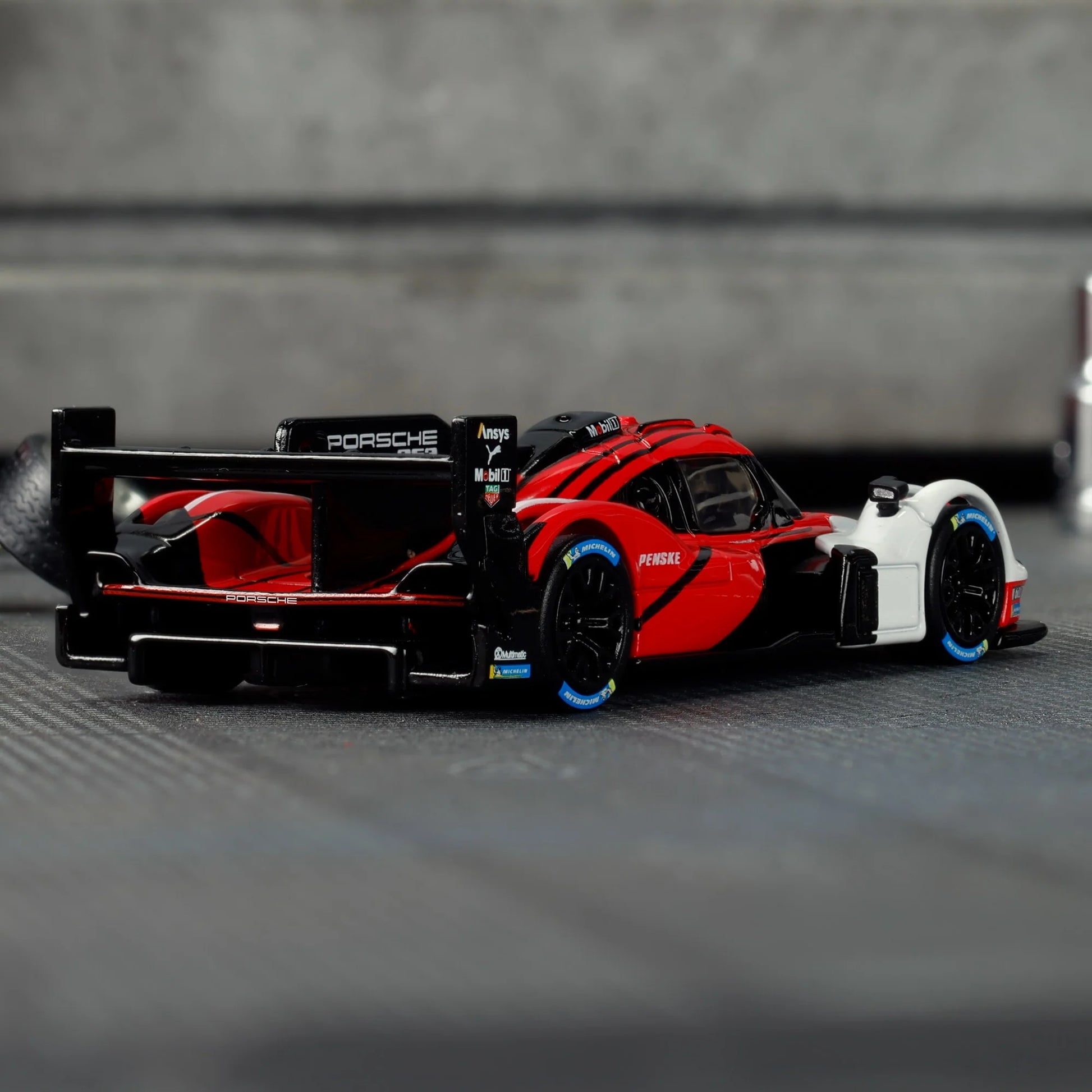 Hot Wheels Elite 64 Porsche 963 in Penske Team livery, featuring red, white, and black racing colors, detailed aero bodywork, and Real Riders wheels.