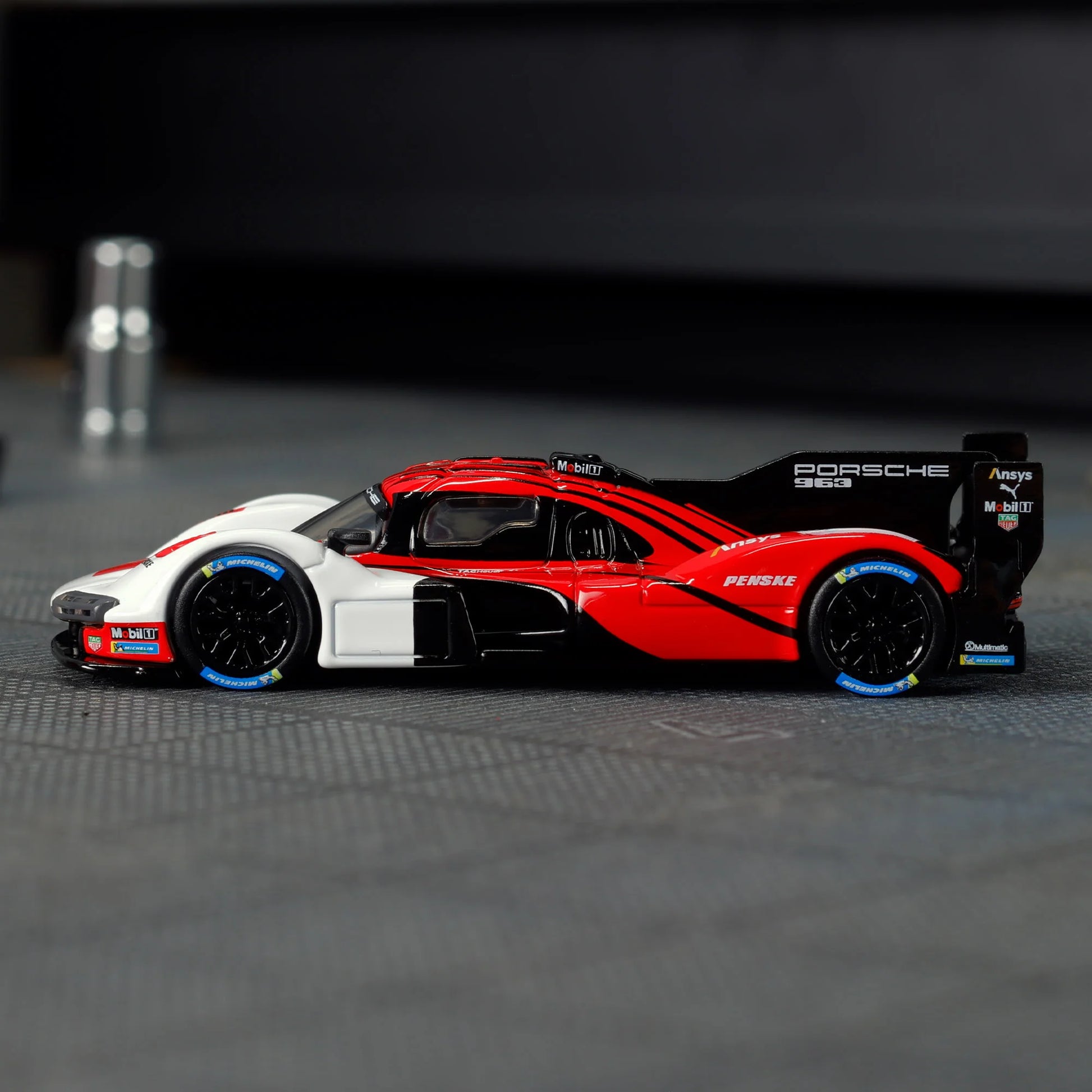 Hot Wheels Elite 64 Porsche 963 in Penske Team livery, featuring red, white, and black racing colors, detailed aero bodywork, and Real Riders wheels.