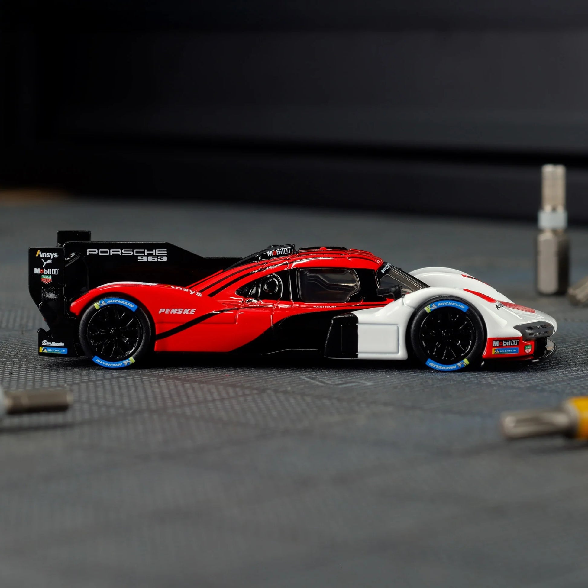 Hot Wheels Elite 64 Porsche 963 in Penske Team livery, featuring red, white, and black racing colors, detailed aero bodywork, and Real Riders wheels.