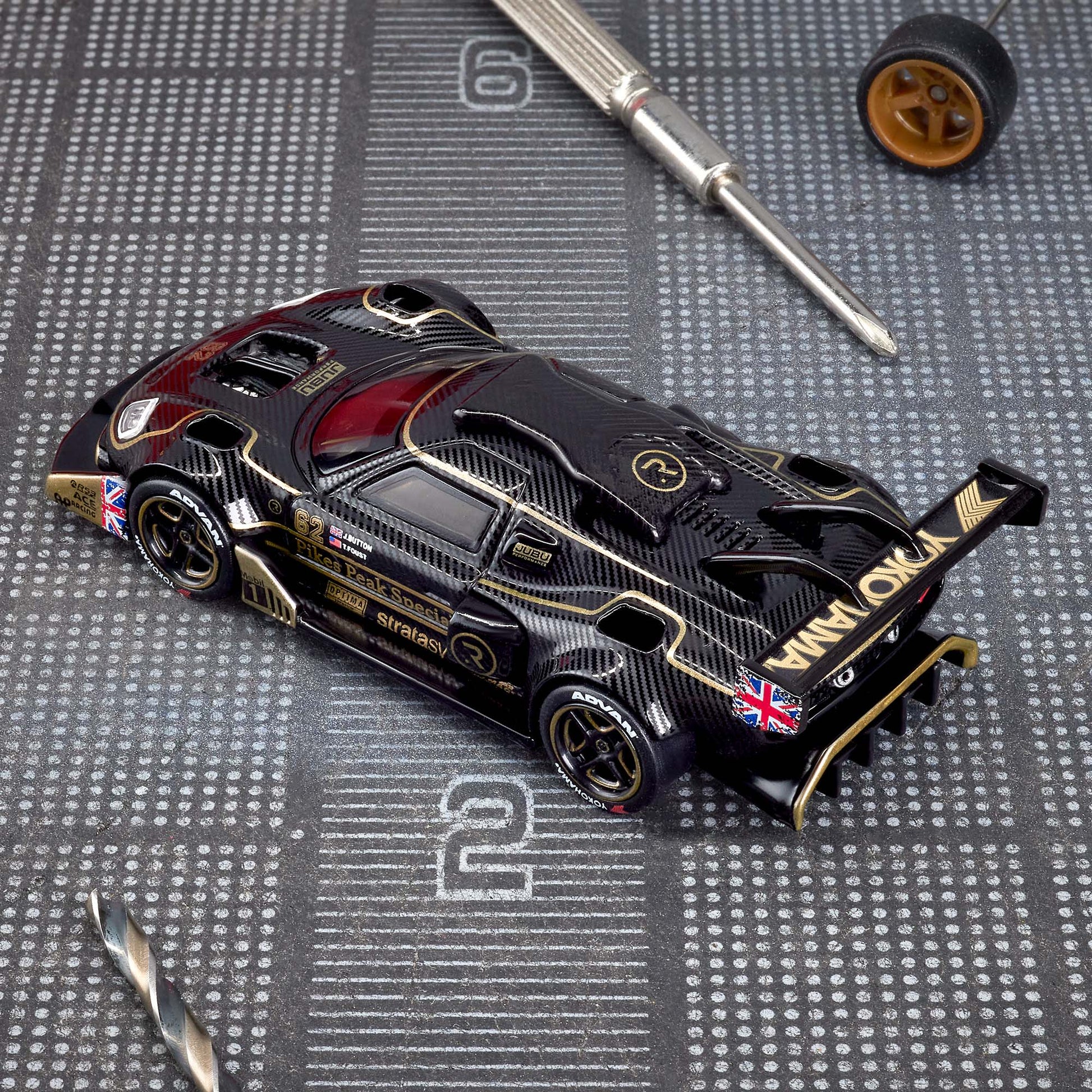 Hot Wheels Elite 64 Radford Type 62-2 Pikes Peak in black and gold JPS livery, featuring aerodynamic bodywork, gold Real Riders wheels, and fine race detailing.