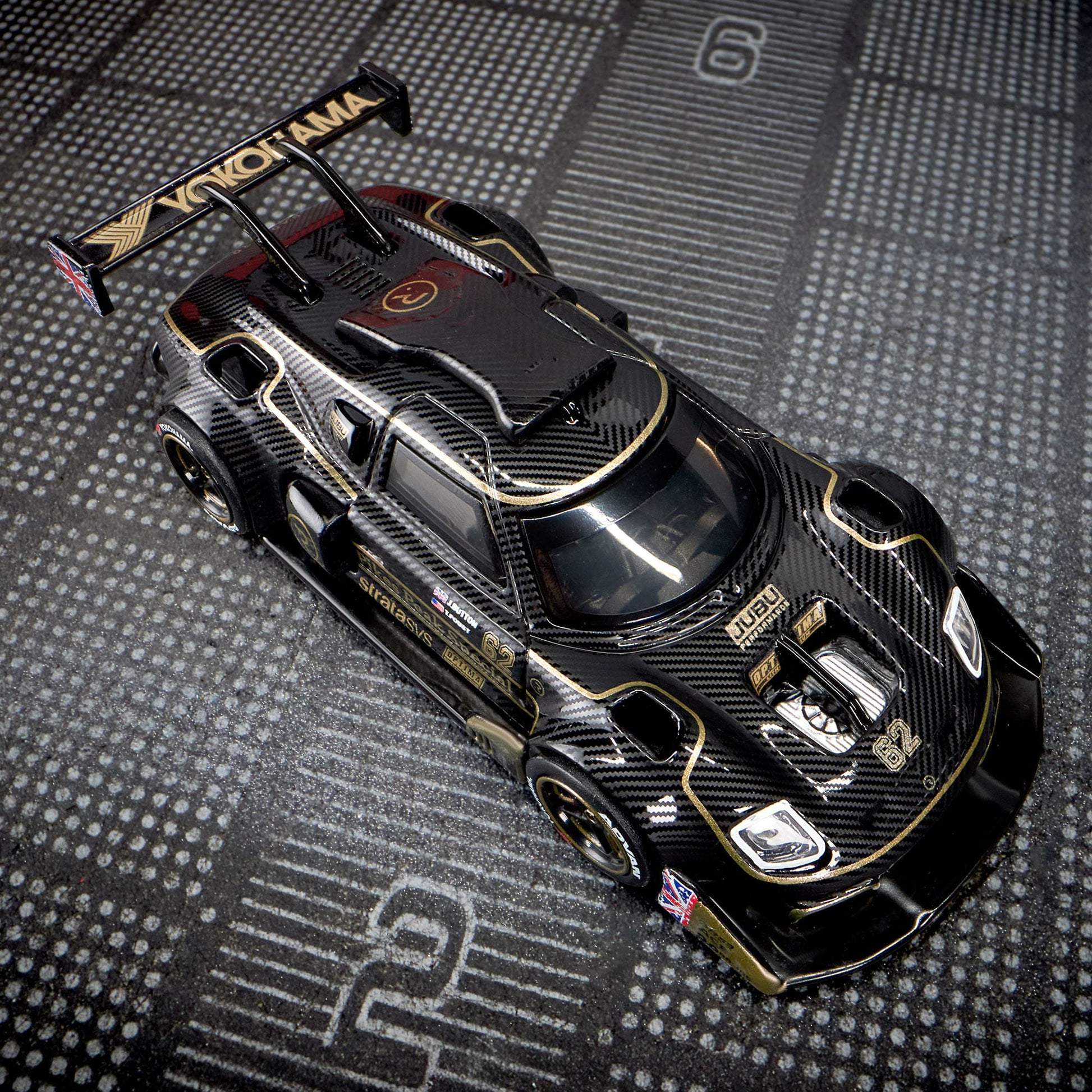 Hot Wheels Elite 64 Radford Type 62-2 Pikes Peak in black and gold JPS livery, featuring aerodynamic bodywork, gold Real Riders wheels, and fine race detailing.