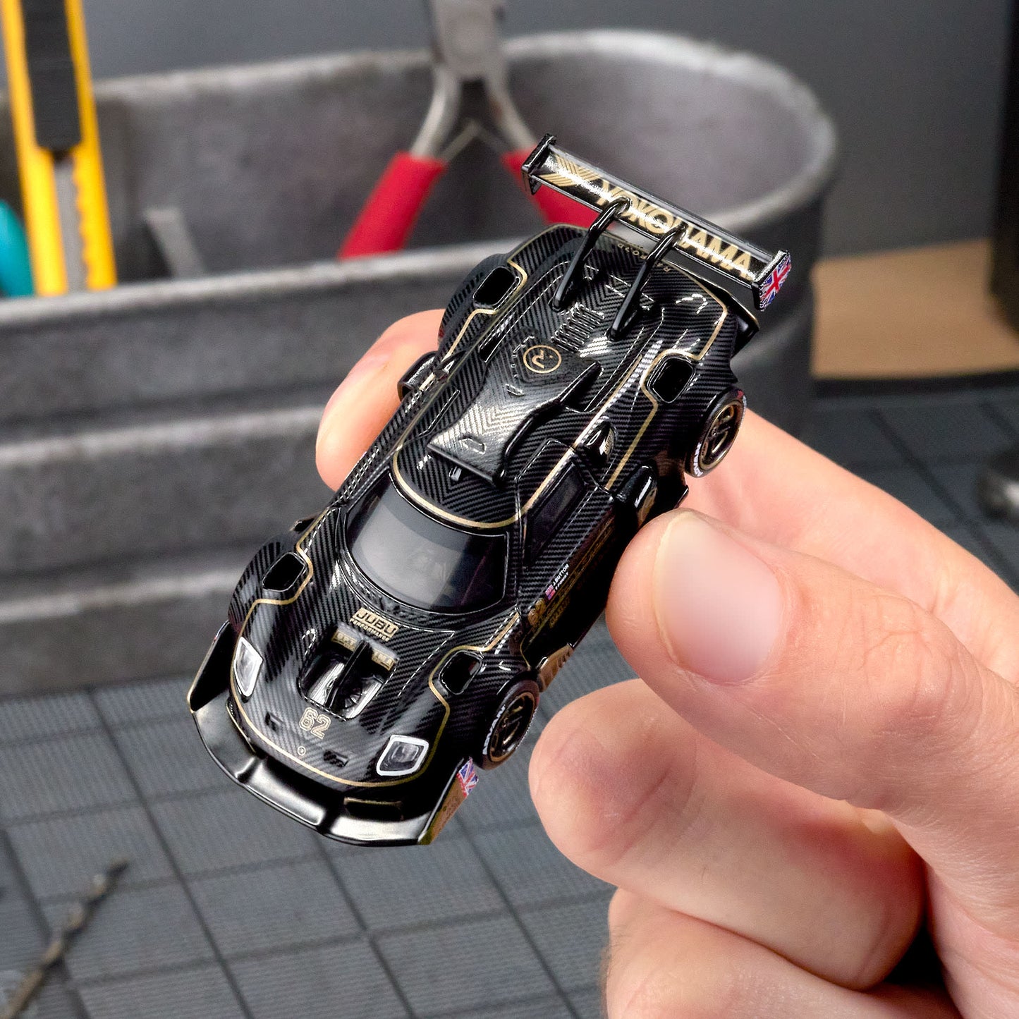 Hot Wheels Elite 64 Radford Type 62-2 Pikes Peak in black and gold JPS livery, featuring aerodynamic bodywork, gold Real Riders wheels, and fine race detailing.
