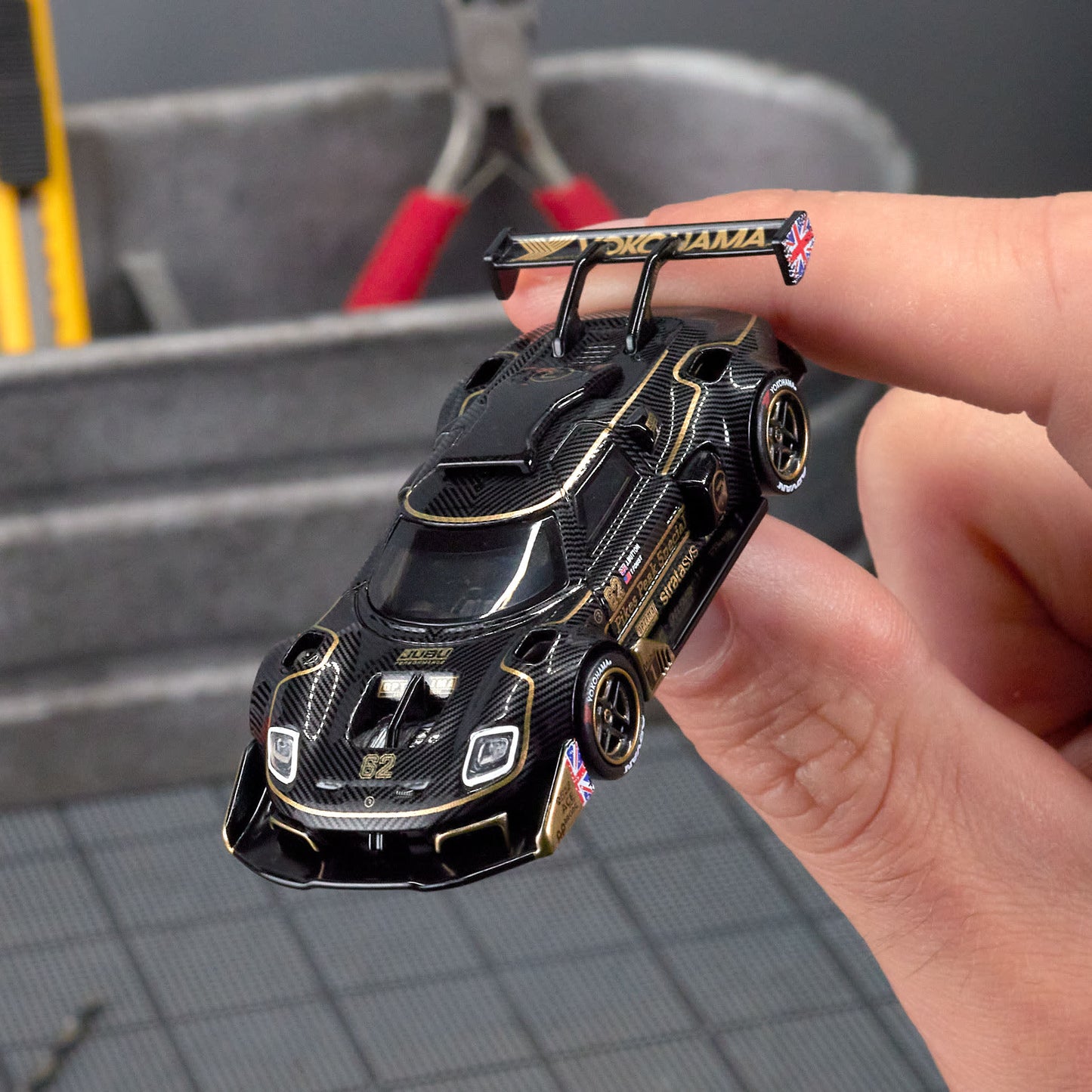 Hot Wheels Elite 64 Radford Type 62-2 Pikes Peak in black and gold JPS livery, featuring aerodynamic bodywork, gold Real Riders wheels, and fine race detailing.