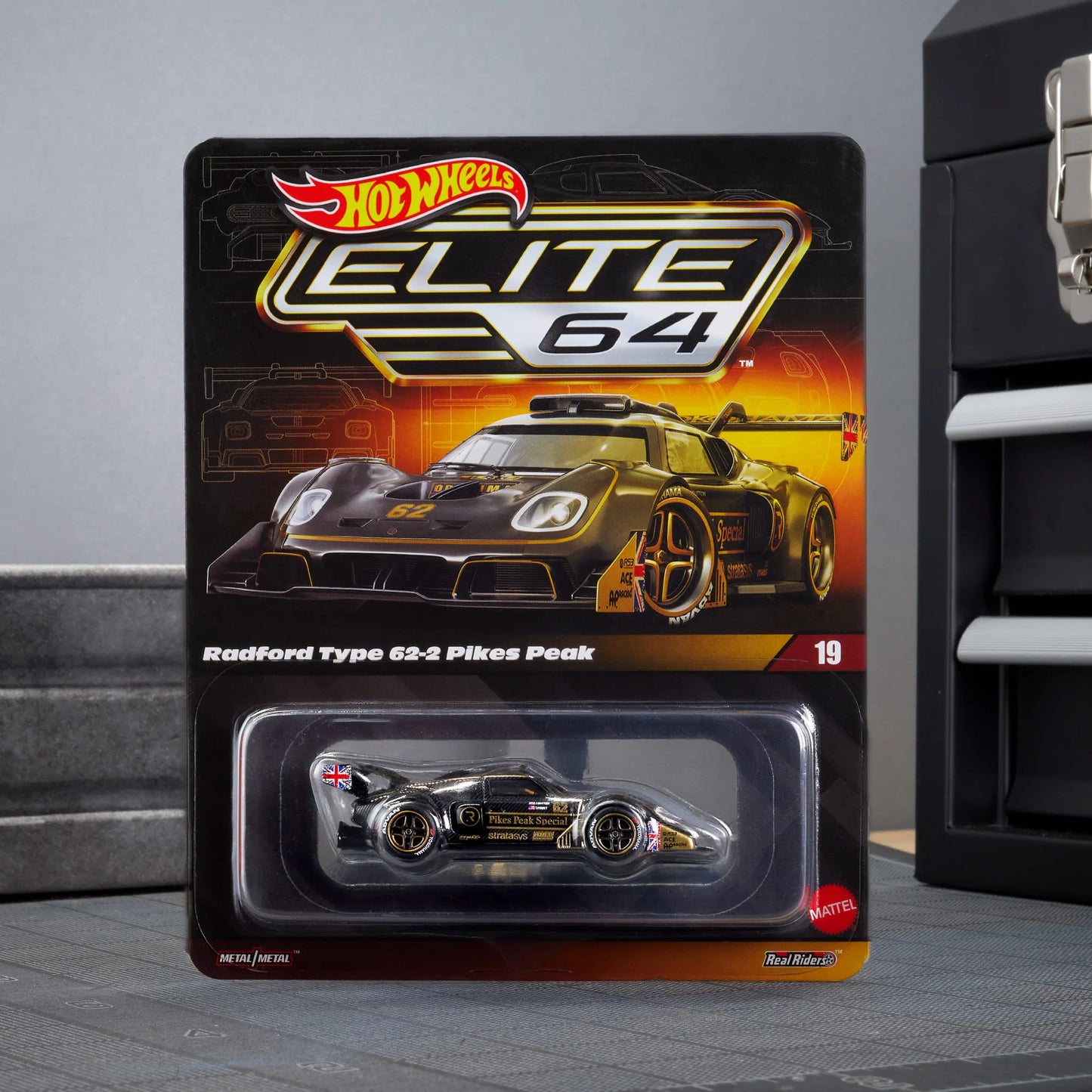 Hot Wheels Elite 64 Radford Type 62-2 Pikes Peak in black and gold JPS livery, featuring aerodynamic bodywork, gold Real Riders wheels, and fine race detailing.