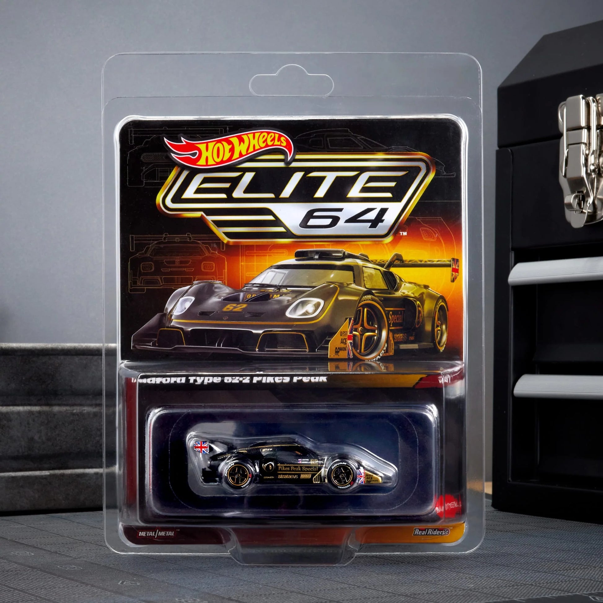 Hot Wheels Elite 64 Radford Type 62-2 Pikes Peak in black and gold JPS livery, featuring aerodynamic bodywork, gold Real Riders wheels, and fine race detailing.