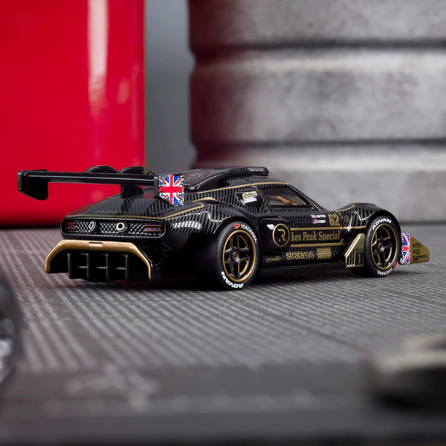 Hot Wheels Elite 64 Radford Type 62-2 Pikes Peak in black and gold JPS livery, featuring aerodynamic bodywork, gold Real Riders wheels, and fine race detailing.