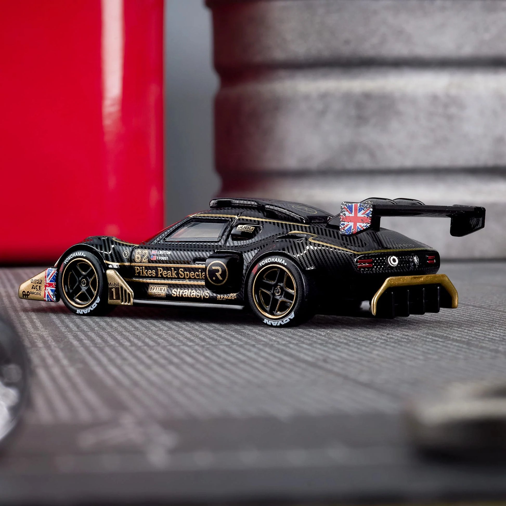 Hot Wheels Elite 64 Radford Type 62-2 Pikes Peak in black and gold JPS livery, featuring aerodynamic bodywork, gold Real Riders wheels, and fine race detailing.