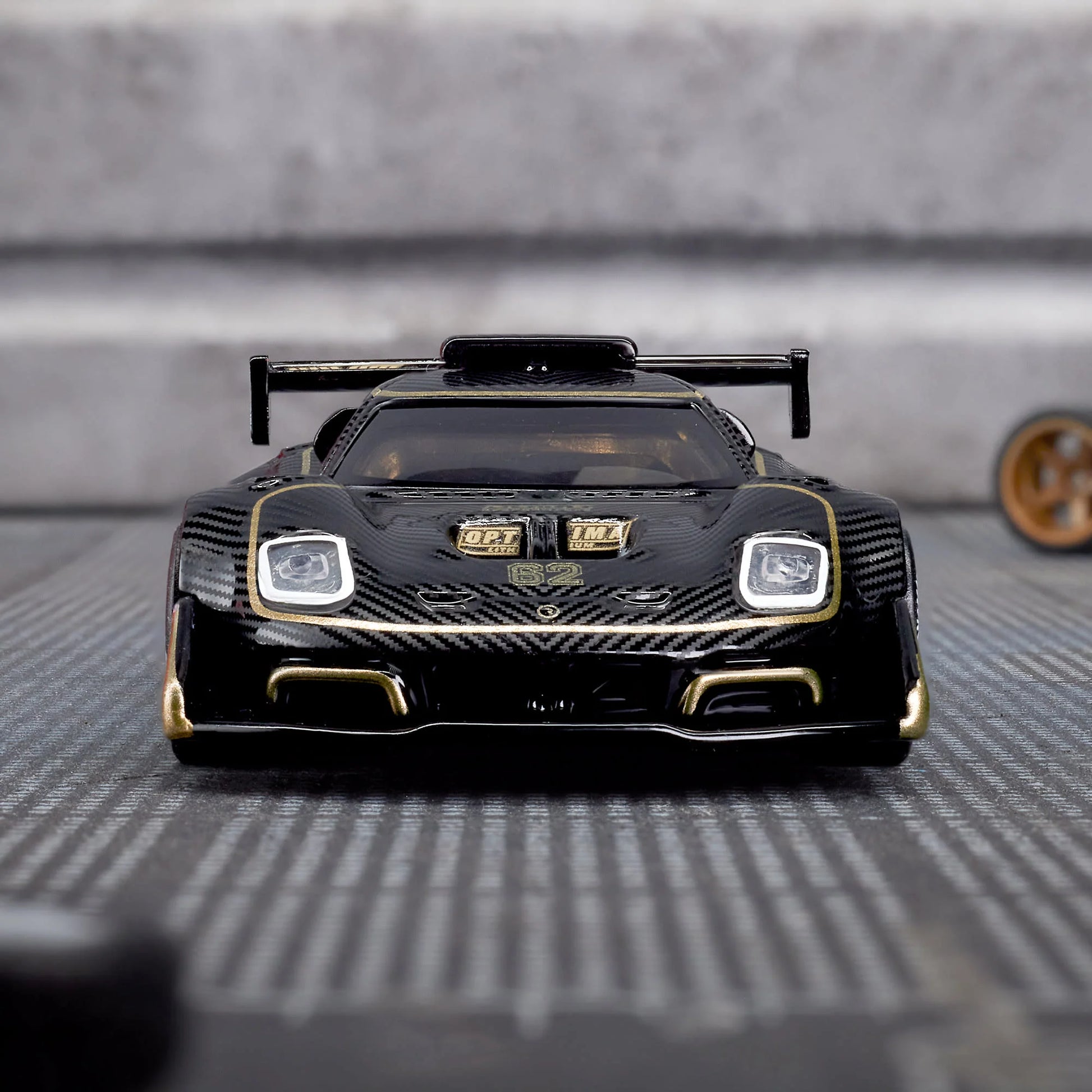 Hot Wheels Elite 64 Radford Type 62-2 Pikes Peak in black and gold JPS livery, featuring aerodynamic bodywork, gold Real Riders wheels, and fine race detailing.
