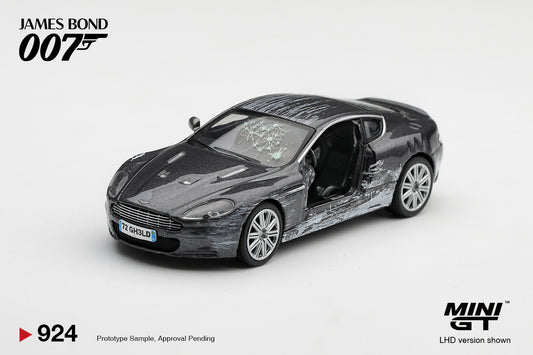 Mini GT battle-damaged Aston Martin DBS from Quantum of Solace 2008 with missing driver's door and shattered windshield.
